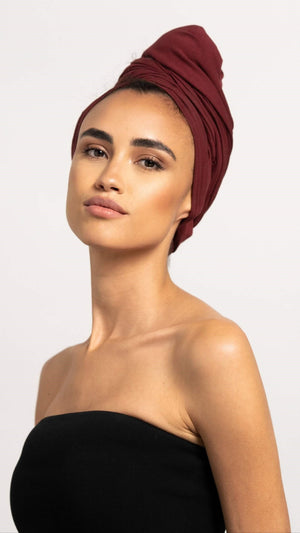 Schöne Frau mit dunklen Haaren trägt ein bordeaux farbenes Bambus Haar Handtuch von Curly'N'Covered als Turban gewickelt