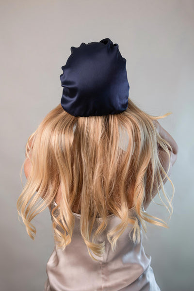 Schöne Frau mit langen blonden Haaren trägt eine Schlaufhaube aus reiner Maulbeerseide in marine blau von CURLY N COVERED zum Schutz ihrer Haare