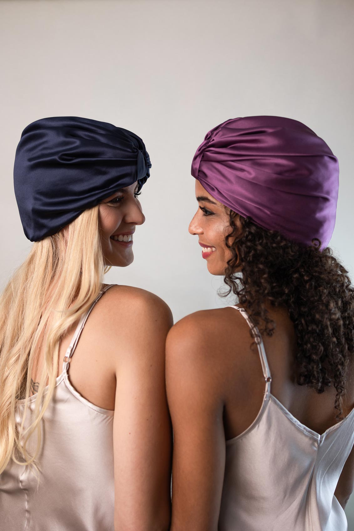 Zwei wunderschöne Frauen tragen Schlafhauben aus reiner Seide von CURLY N COVERED zum Schutz ihrer Haare und Locken