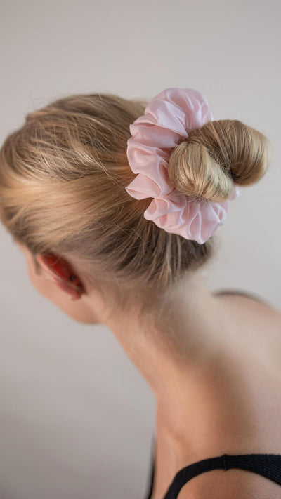 Wunderschöne Frau mit blonden Haaren trägt einen blass rosa Scrunchie aus Cotton Silk (Baumwolle und Seide) von Curly N Covered im Haar.