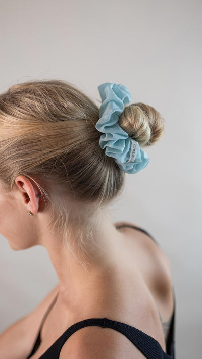 Wunderschöne Frau mit blonden Haaren trägt einen hell blauen Scrunchie aus Cotton Silk (Baumwolle und Seide) von Curly N Covered im Haar.