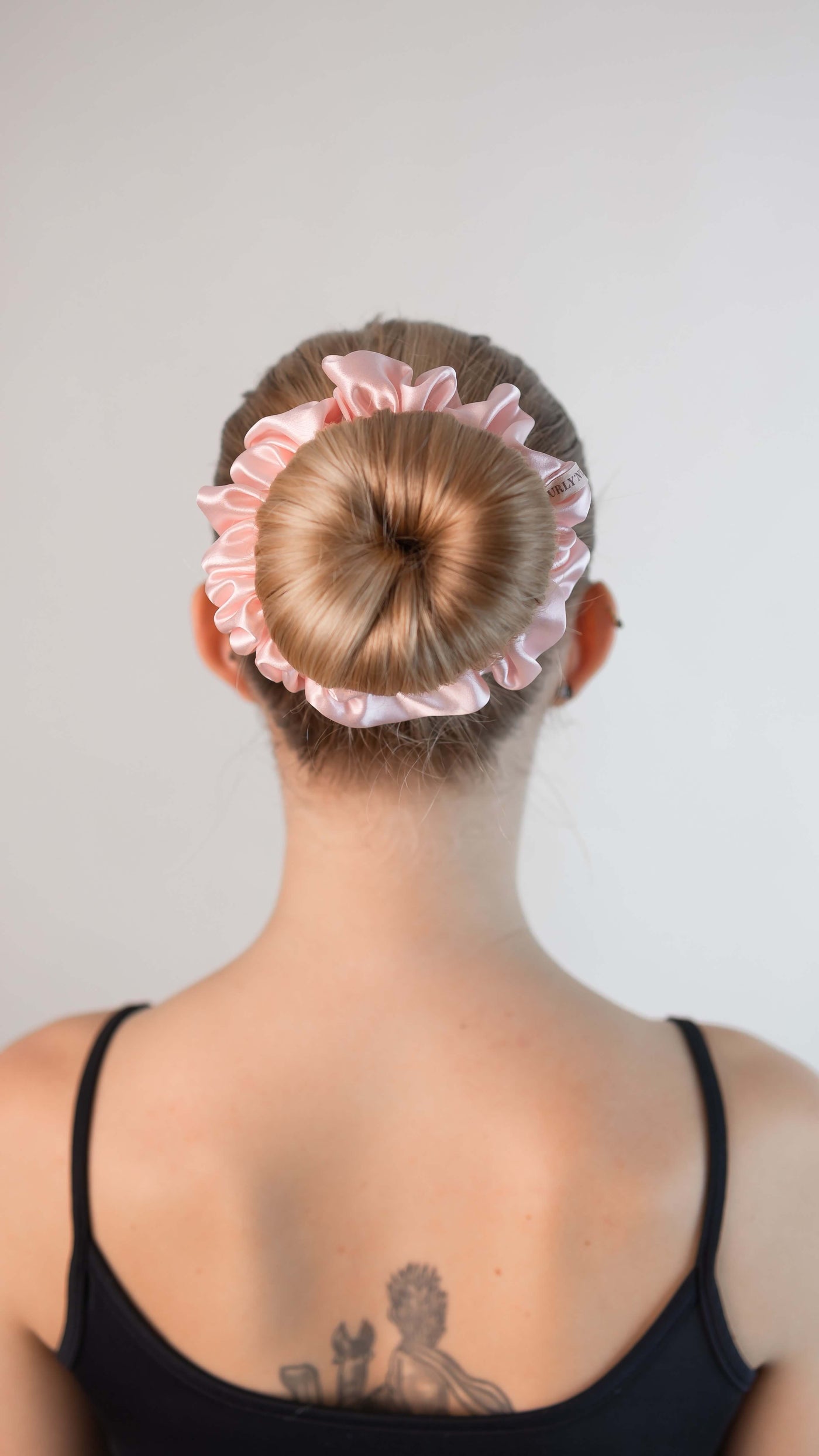 Schöne Frau mit blonden Haaren trägt einen Scrunchie aus reiner Maulbeer-Seide in zart rosa von Curly N Covered im Haar
