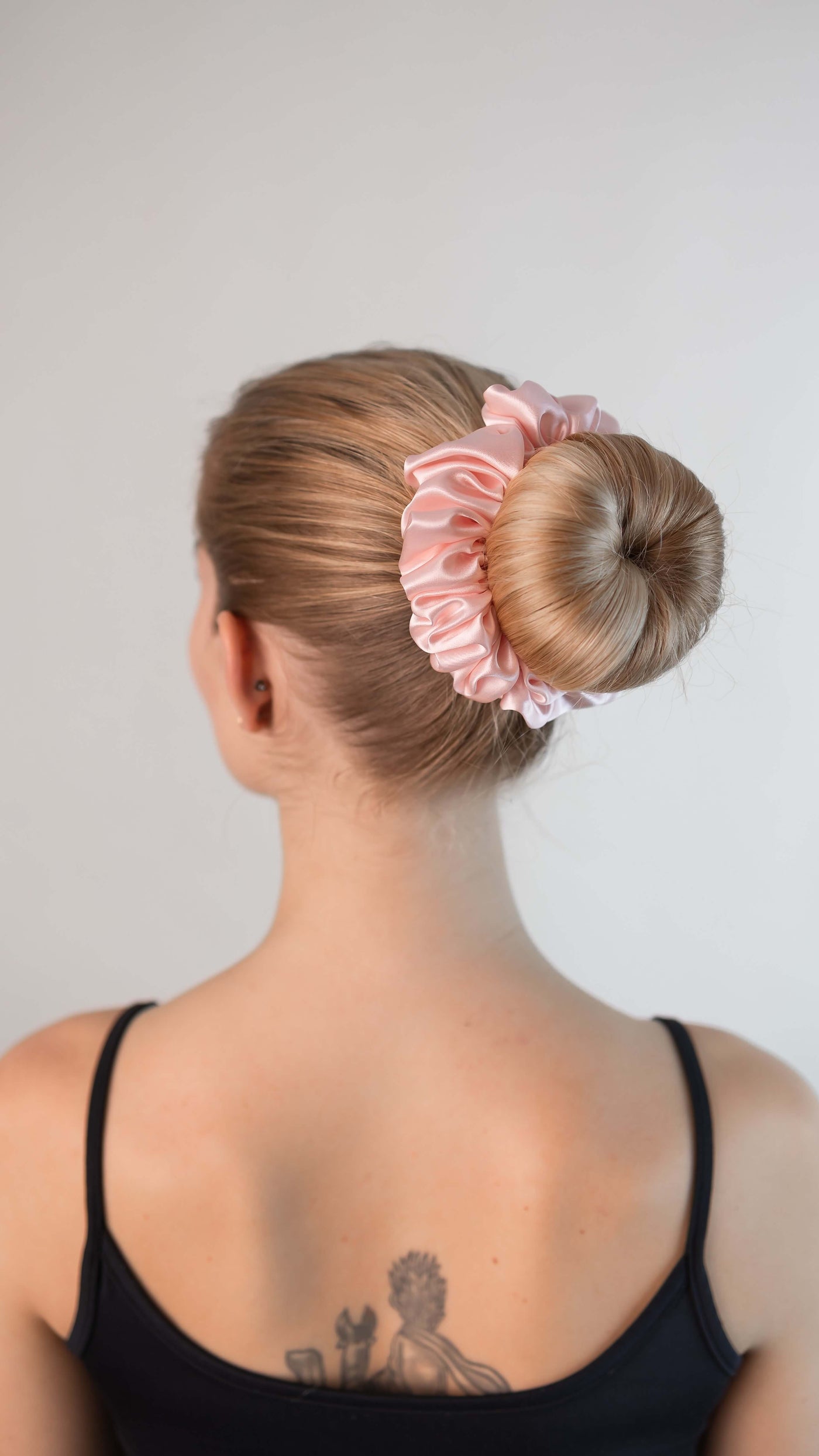 Wunderschöne Frau mit blonden Haaren trägt einen Scrunchie aus reiner Maulbeer-Seide in zart rosa von Curly N Covered im Haar
