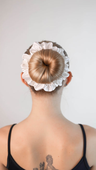 Schöne Frau mit blonden Haaren trägt einen Scrunchie aus reiner Maulbeer-Seide in creme weiß von Curly N Covered im Haar