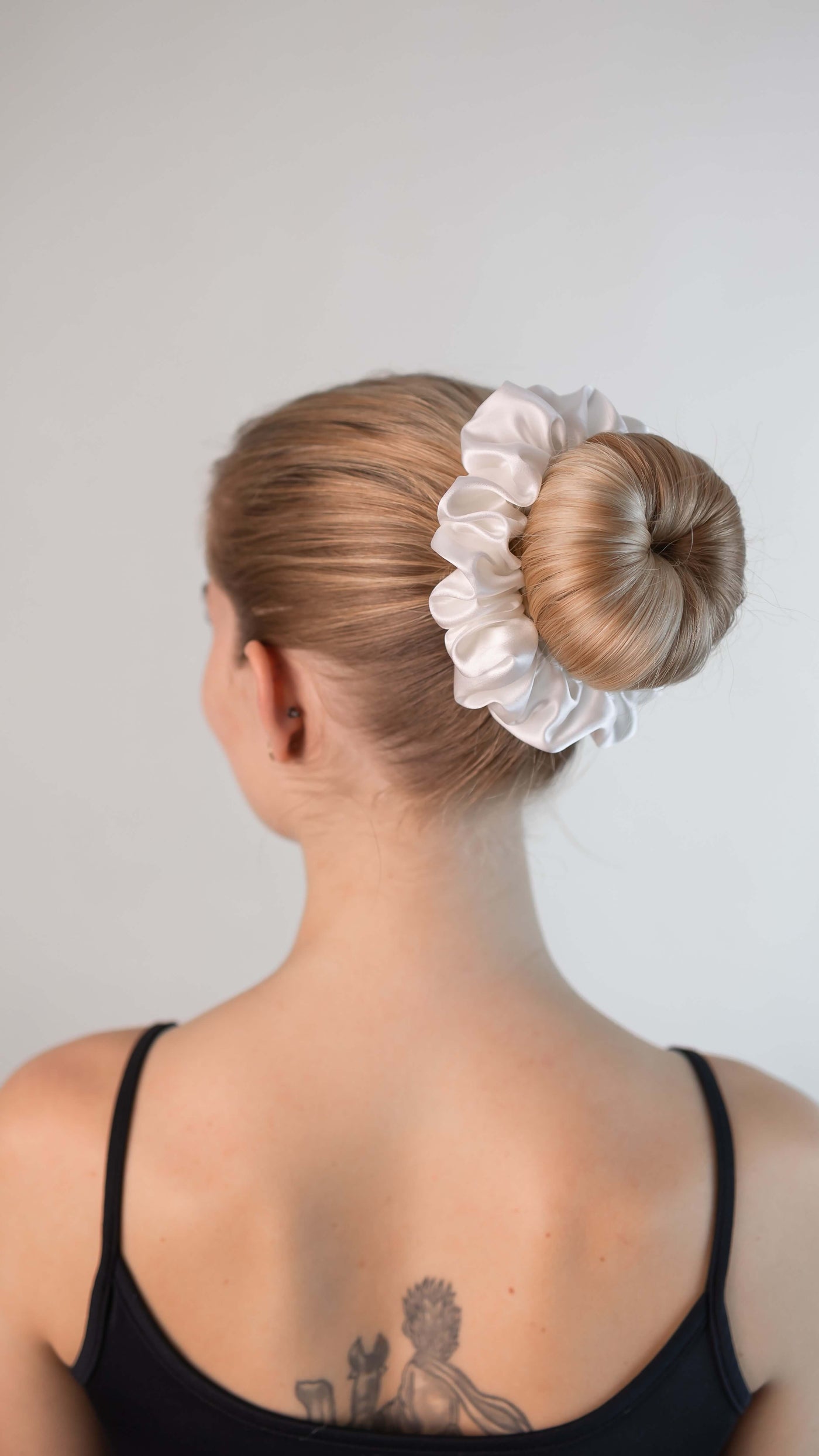 Wunderschöne Frau mit blonden Haaren trägt einen Scrunchie aus reiner Maulbeer-Seide in creme weiß von Curly N Covered im Haar