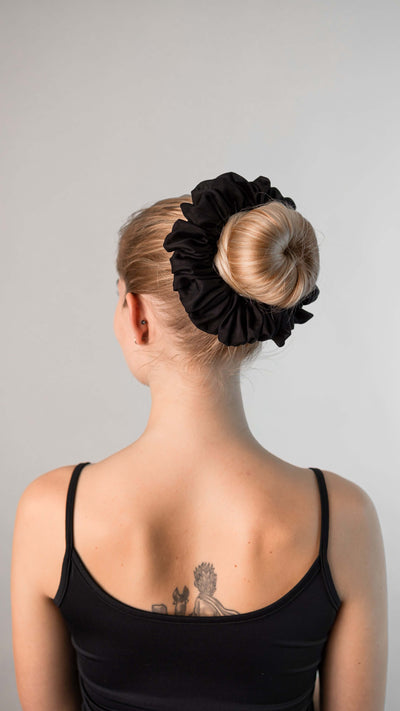 Schöne Frau mit blonden Haaren trägt einen schwarzen XXL Scrunchie aus Cotton Silk (Baumwolle und Seide) von Curly N Covered im Haar.