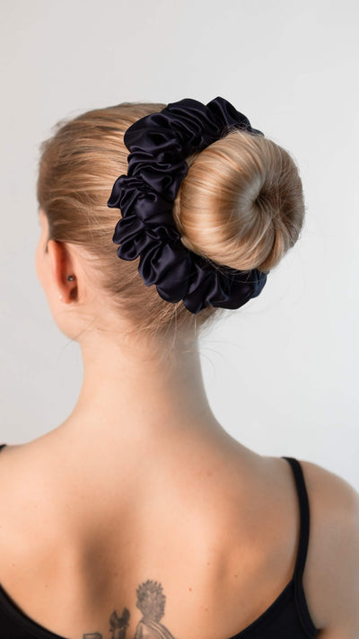 Wunderschöne Frau mit blonden Haaren trägt einen XXL Scrunchie aus reiner Maulbeer-Seide in marine blau von Curly N Covered im Haar